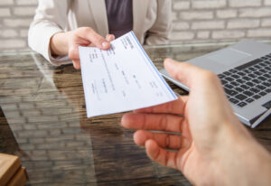 Business woman paying with check to her colleague Business woman paying with check to her colleague